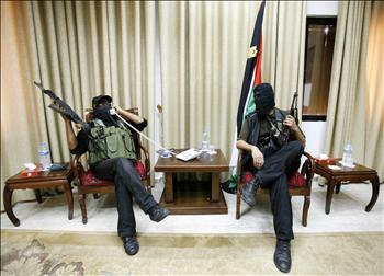مقاتلان من حماس أحدهما يتحدث على الهاتف في قاعة الاستقبالات الرسمية لرئيس السلطة محمود عباس في مقره في غزة أمس 